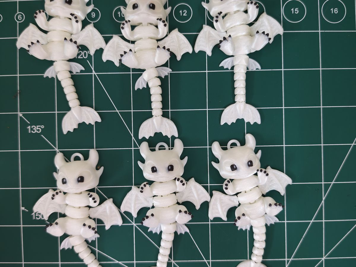 Six white articulated dragons laid out on a cutting mat